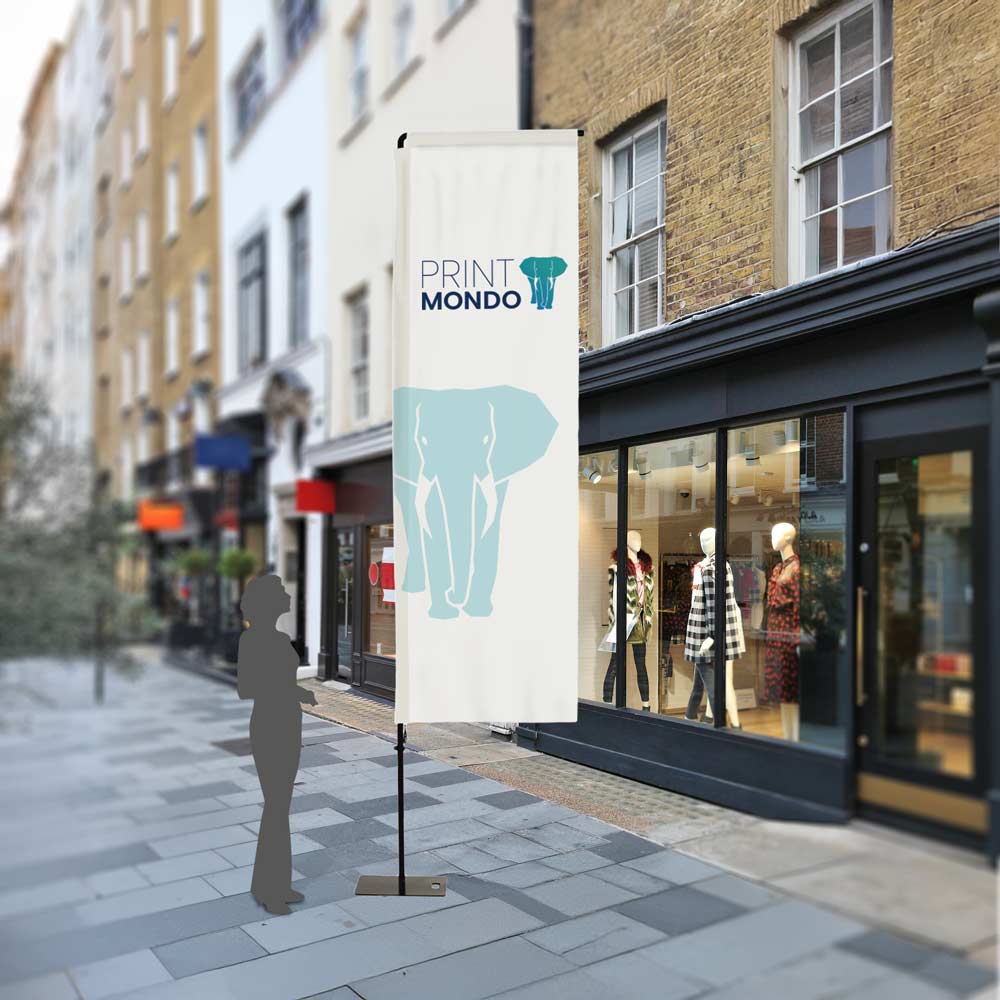 Beispielbild Outdoorflag Square im Außeneinsatz mit Schattenperson daneben als Größenvergleich. Hier mit Beispieldruck in türkis und blau mit dem Print Mondo Elefanten Logo.