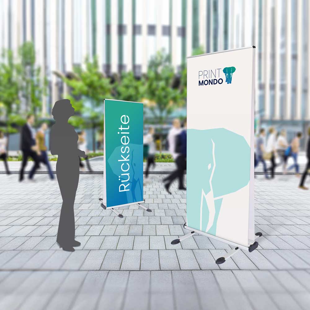 Darstellung des Roll Up Outdoor Double auf dem Gelände eines Bürogebäudes mit Schattenperson daneben um die Größe darzustellen.