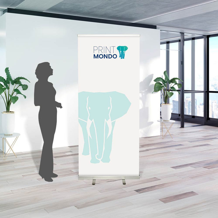 Beispielbild Roll Up im Einsatz in einem Büro mit Schattenperson daneben zum größenvergleich. Hier mit Beispieldruck in weiss, türkis und blau mit dem Print Mondo Elefanten Logo.