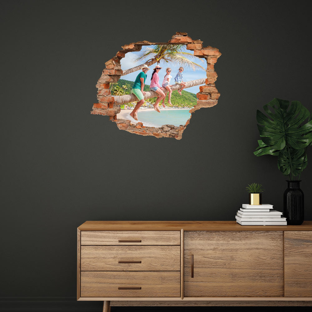 3D-Wandtattoo mit realistischem Mauerdurchbruch-Effekt und tropischem Familien-Urlaubsfoto – kreative Wanddekoration von Printmondo. Hier an einer grauen Wand über einer Holz-Kommode verklebt.