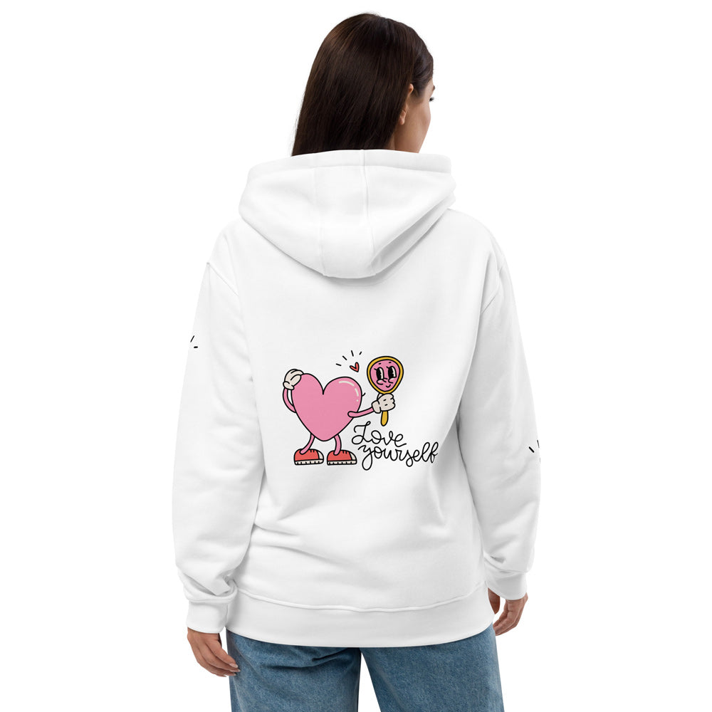 Eine Frau trägt einen weißen Hoodie mit Kapuze und lockerer Passform. Auf der Rückseite ist eine niedliche Grafik mit einem pinken Herz zu sehen, das in einen Spiegel schaut, kombiniert mit dem Schriftzug „Love Yourself“. Der Hoodie ist bequem und stylisch zugleich, perfekt für ein positives Statement im Alltag.