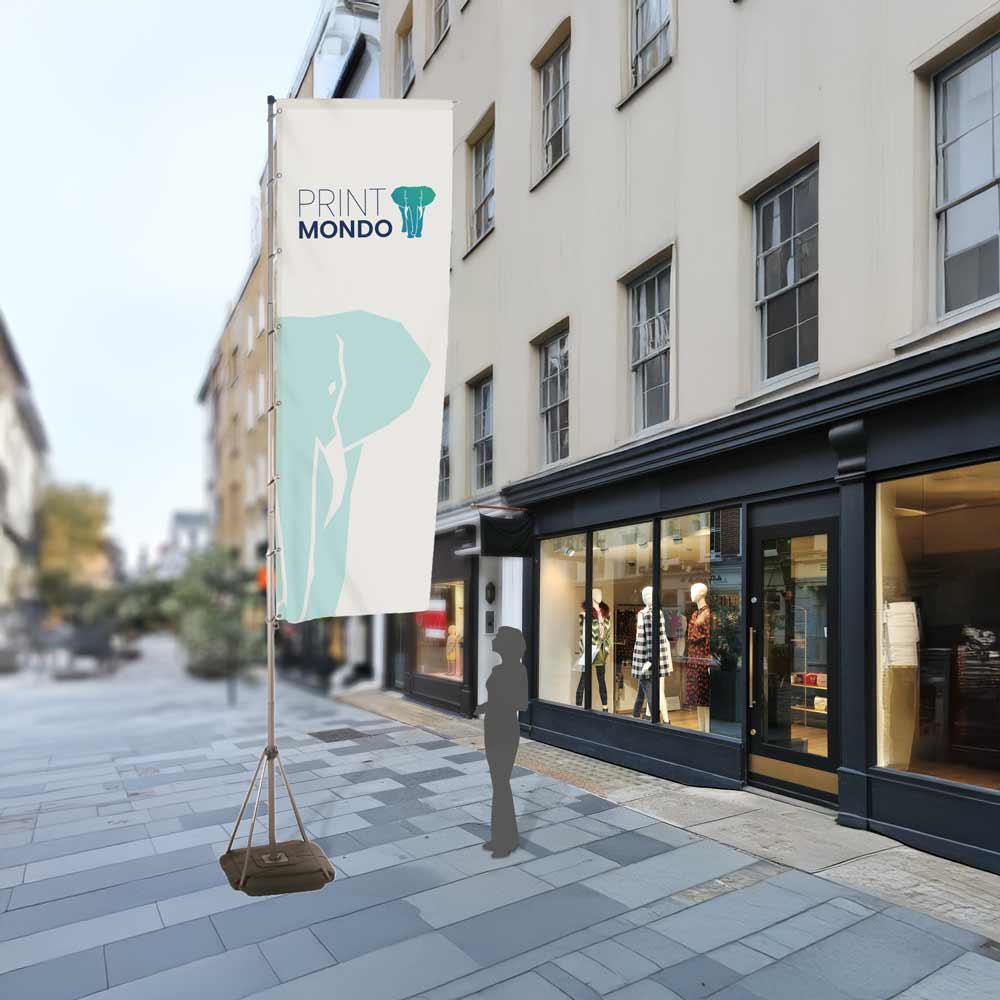 Beispielbild Mega Outdoorflag 540 im Außeneinsatz mit Schattenperson daneben als Größenvergleich. Auf der Straße hier mit Beispieldruck in weiss, türkis und blau mit dem Print Mondo Elefanten Logo.